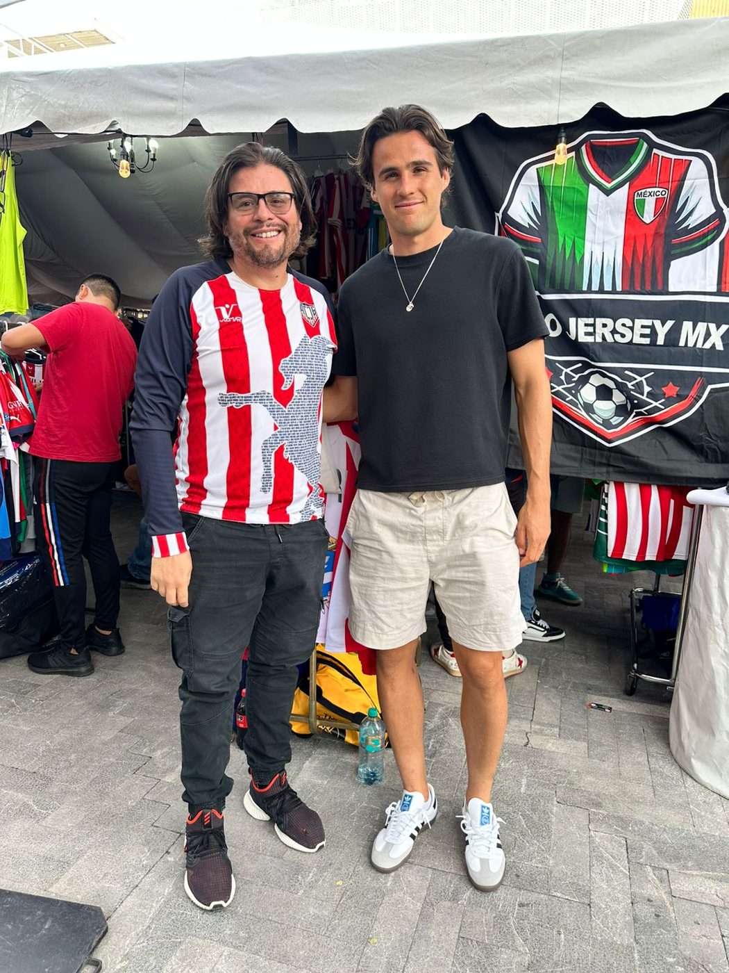 Coleccionista mostrando jersey clásico rojiblanco a otro asistente