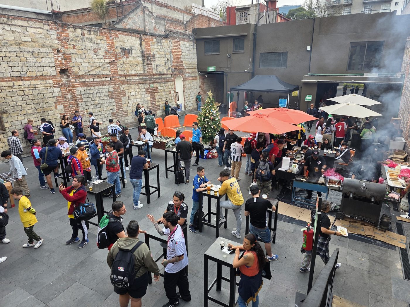 Patio del evento: asistentes comiendo, tomando, jugando futbolito y conviviendo entre stands