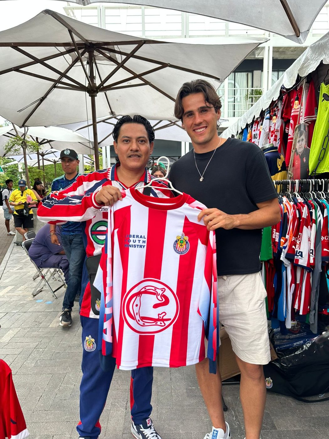 Coleccionista con jersey rojiblanco posando junto a un visitante en el stand de Expo Jersey MX